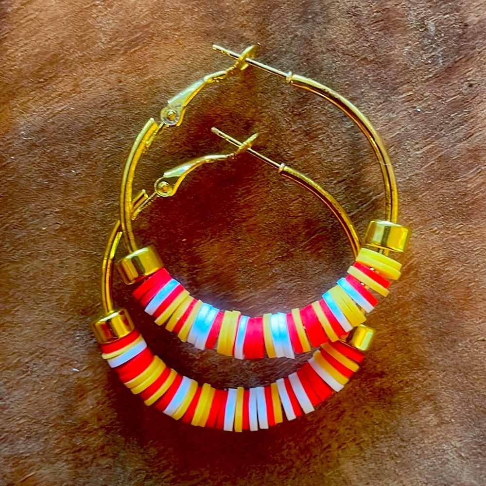 Handmade yellow gold hoop earrings with red and yellow beads and gold accents.